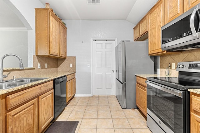kitchen with light tile patterned floors, arched walkways, a sink, decorative backsplash, and appliances with stainless steel finishes