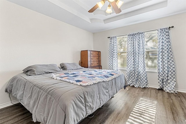 bedroom featuring baseboards, a ceiling fan, wood finished floors, and a raised ceiling