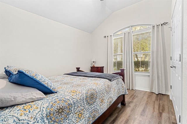bedroom with vaulted ceiling and wood finished floors