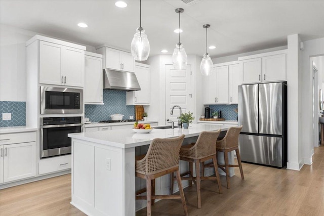 7913 Edmondson Bnd, Austin, TX 78744 - kitchen with stainless steel appliances, under cabinet range hood, decorative backsplash, recessed lighting, and a breakfast bar area