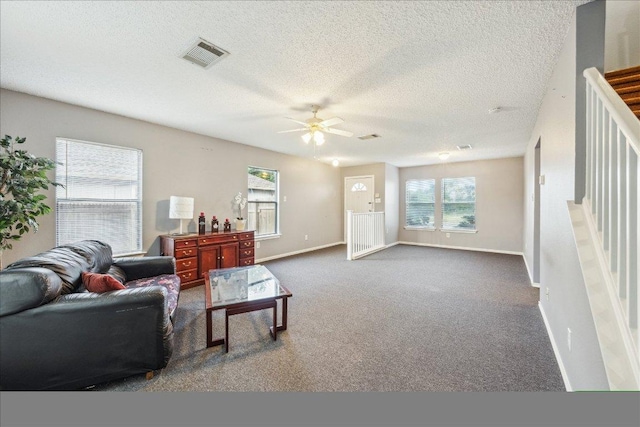 carpeted living area with baseboards, visible vents, a textured ceiling, and ceiling fan