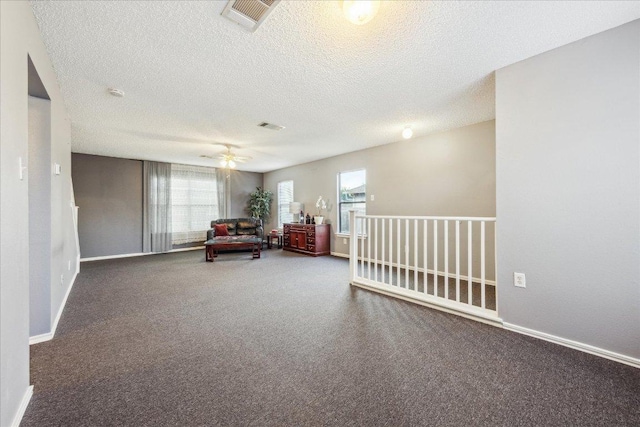 living area with dark carpet, baseboards, a textured ceiling, and visible vents