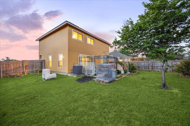 rear view of house with a lawn, a fenced backyard, and cooling unit