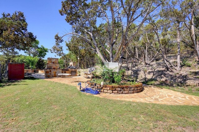 view of yard featuring a patio area and an outdoor stone fireplace
