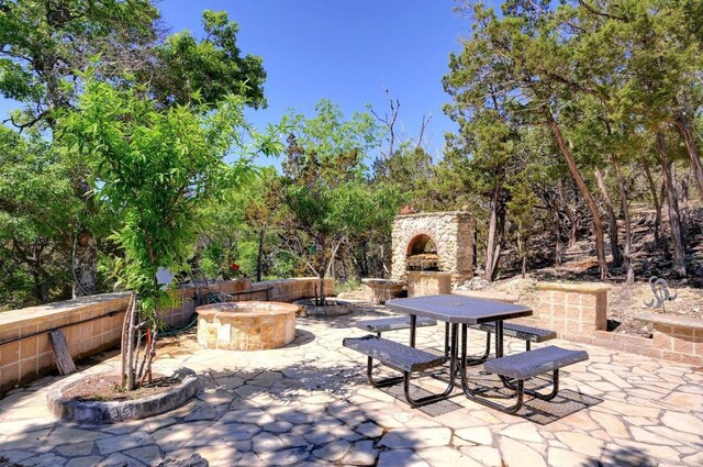 view of patio featuring an outdoor stone fireplace and an outdoor fire pit