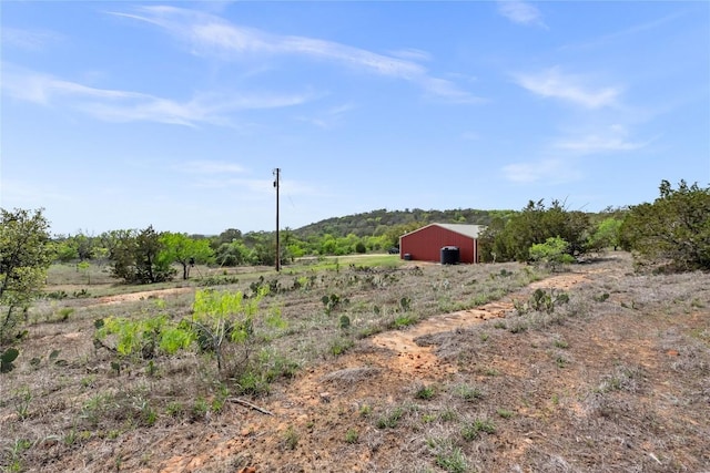 view of yard featuring a rural view, a pole building, and an outbuilding