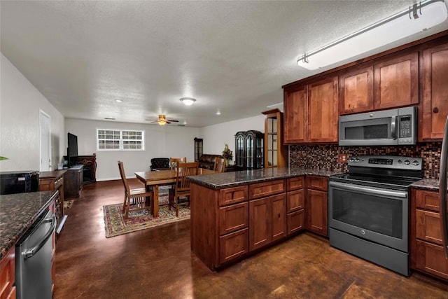 kitchen with brown cabinetry, backsplash, a peninsula, and appliances with stainless steel finishes
