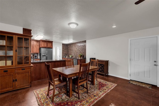 dining room featuring a textured ceiling, concrete flooring, and baseboards