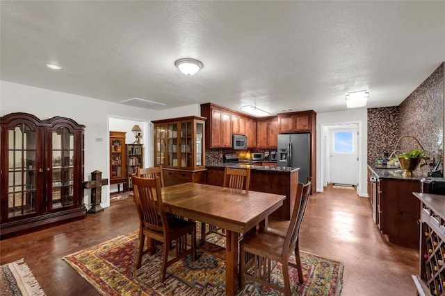 dining space featuring a textured ceiling, finished concrete flooring, and baseboards