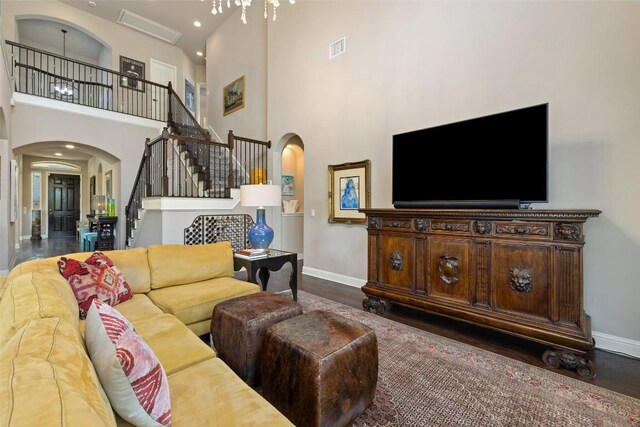 living area featuring a towering ceiling, baseboards, arched walkways, and stairs