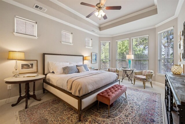 carpeted bedroom featuring baseboards, ornamental molding, visible vents, and a raised ceiling