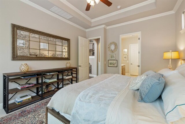 bedroom featuring connected bathroom, baseboards, ornamental molding, and a raised ceiling
