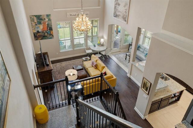 stairs featuring arched walkways, baseboards, a chandelier, a high ceiling, and wood finished floors