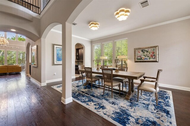 dining room featuring dark wood-type flooring, arched walkways, visible vents, and baseboards