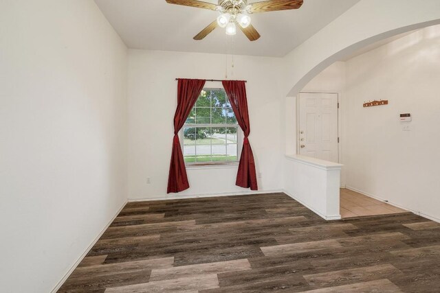 unfurnished room with ceiling fan, arched walkways, and wood finished floors
