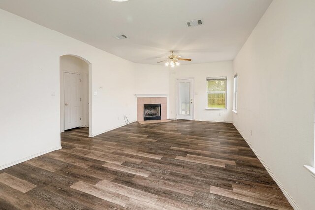 unfurnished living room featuring arched walkways, dark wood finished floors, visible vents, and a ceiling fan
