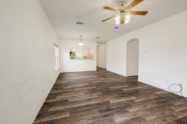 empty room featuring dark wood-style floors, arched walkways, a ceiling fan, and visible vents