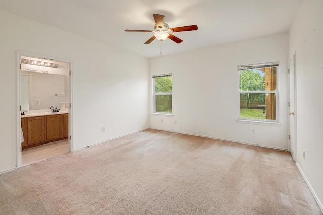 unfurnished bedroom with ensuite bath, ceiling fan, light carpet, and a sink