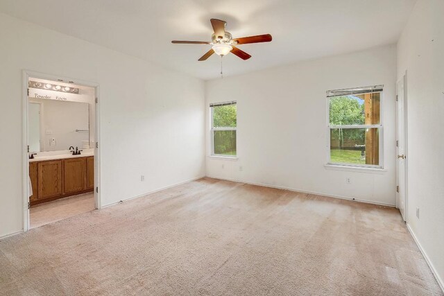 408 Wiley St, Hutto, TX 78634 - unfurnished bedroom featuring light colored carpet, a sink, ensuite bathroom, and a ceiling fan