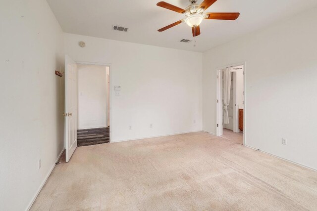 spare room with visible vents, a ceiling fan, and light colored carpet