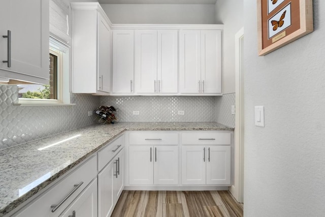 20401 Great Egret Ln, Pflugerville, TX 78660 - kitchen featuring tasteful backsplash, white cabinets, light wood finished floors, and light stone counters
