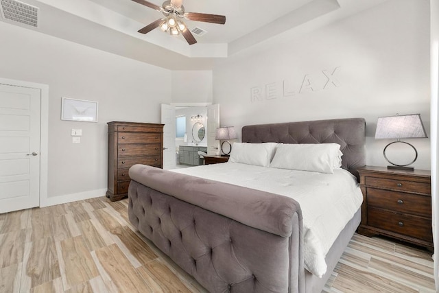 20401 Great Egret Ln, Pflugerville, TX 78660 - bedroom featuring a tray ceiling, light wood finished floors, ensuite bathroom, and ceiling fan
