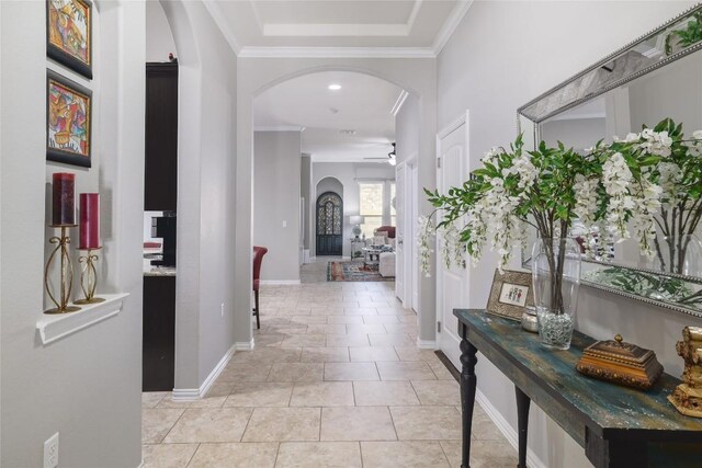 hallway featuring baseboards, arched walkways, and ornamental molding