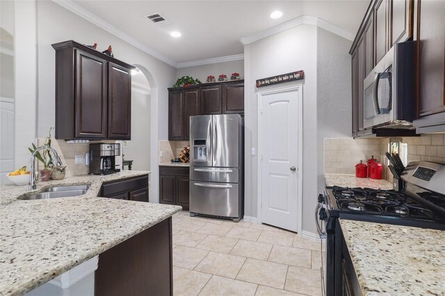 kitchen with a sink, visible vents, dark brown cabinetry, decorative backsplash, and appliances with stainless steel finishes