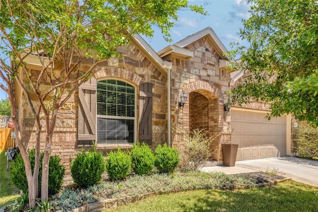 view of front facade featuring stone siding, an attached garage, and driveway