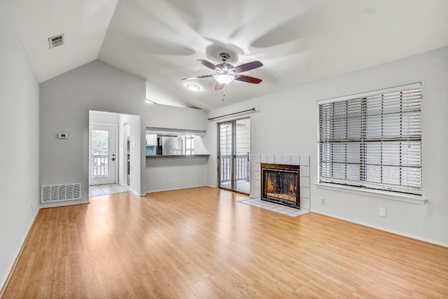 2215 Post Rd Unit 2022, Austin, TX 78704 - unfurnished living room with ceiling fan, wood finished floors, lofted ceiling, a tile fireplace, and baseboards