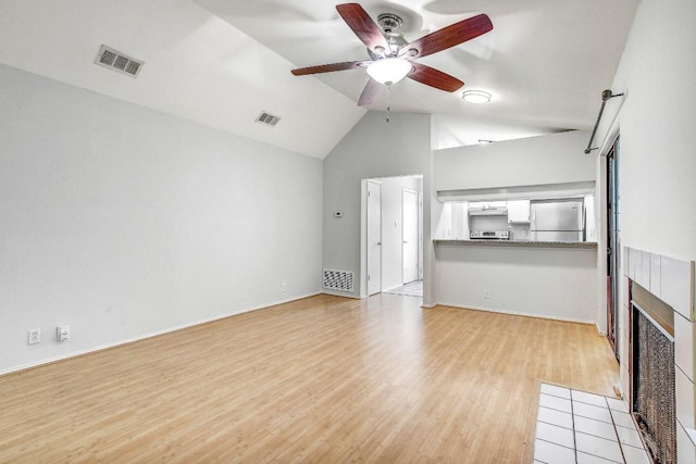 2215 Post Rd Unit 2022, Austin, TX 78704 - unfurnished living room featuring a ceiling fan, light wood finished floors, a tile fireplace, lofted ceiling, and baseboards
