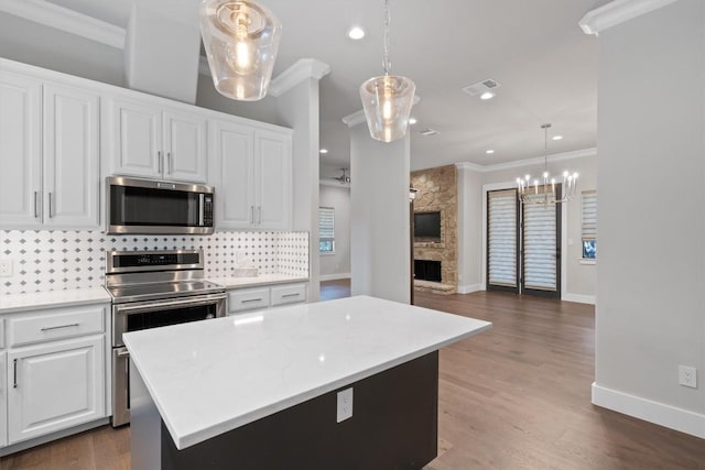 8 Cove Creek Ln, Austin, TX 78738 - kitchen with stainless steel appliances, crown molding, tasteful backsplash, a stone fireplace, and white cabinetry