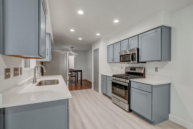 12319 Wycliff Ln, Austin, TX 78727 - kitchen with stainless steel appliances, gray cabinetry, a sink, light wood-style flooring, and baseboards