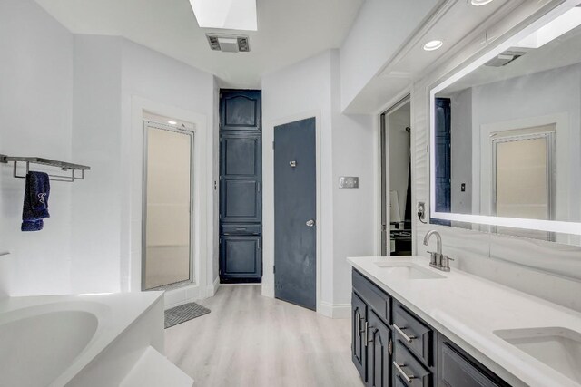 12319 Wycliff Ln, Austin, TX 78727 - bathroom featuring double vanity, wood finished floors, a garden tub, and baseboards