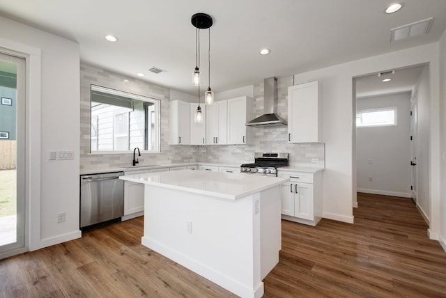 407 Delmar Ave Unit A, Austin, TX 78752 - kitchen featuring stainless steel appliances, wall chimney exhaust hood, decorative backsplash, white cabinets, and light countertops