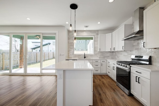 kitchen featuring a center island, stainless steel range with gas stovetop, dark wood-style flooring, tasteful backsplash, and wall chimney range hood