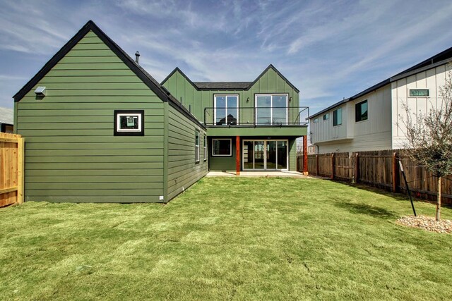rear view of property with a fenced backyard, a patio, a balcony, and a lawn