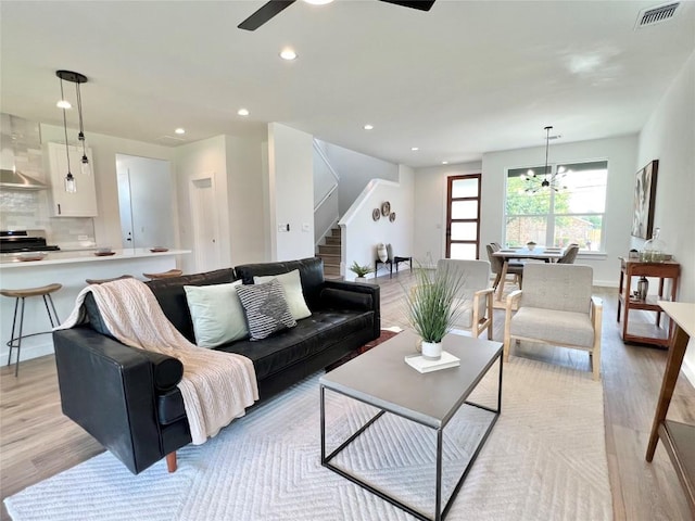 living room with light wood-type flooring, a ceiling fan, recessed lighting, and stairway