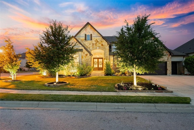2500 Yuma Trl, Leander, TX 78641 - french country inspired facade featuring stone siding, french doors, concrete driveway, a front yard, and an attached garage