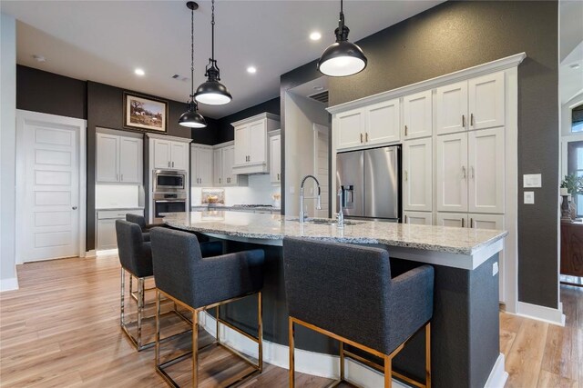 2500 Yuma Trl, Leander, TX 78641 - kitchen with appliances with stainless steel finishes, white cabinetry, light wood-type flooring, light stone countertops, and recessed lighting
