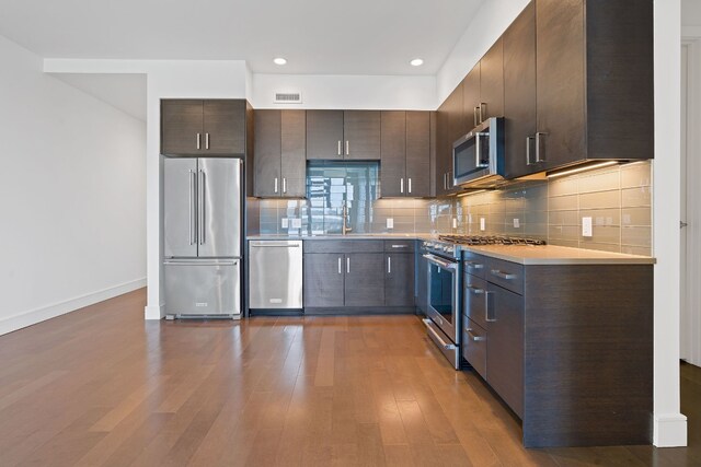 kitchen featuring dark brown cabinetry, light countertops, visible vents, and premium appliances