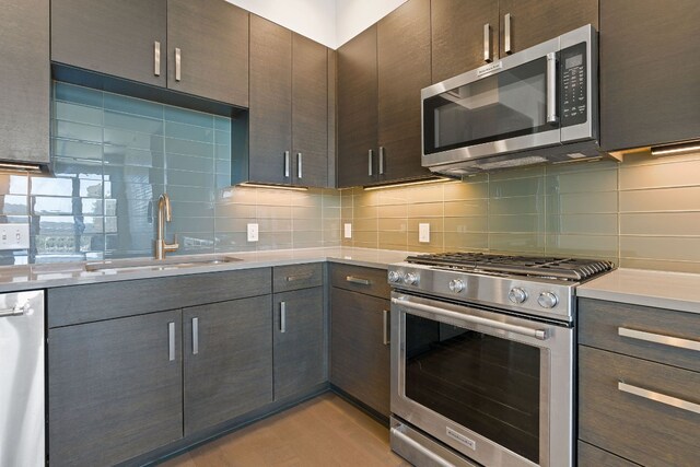 kitchen featuring stainless steel appliances, light countertops, a sink, dark brown cabinetry, and decorative backsplash