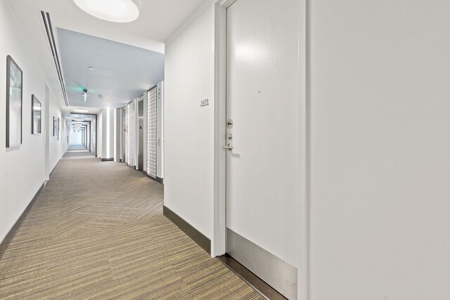hallway featuring carpet floors and baseboards