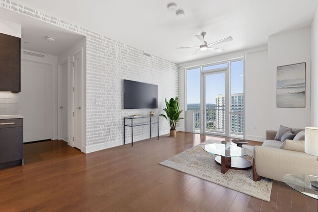 living area with visible vents, baseboards, an accent wall, wood finished floors, and ceiling fan