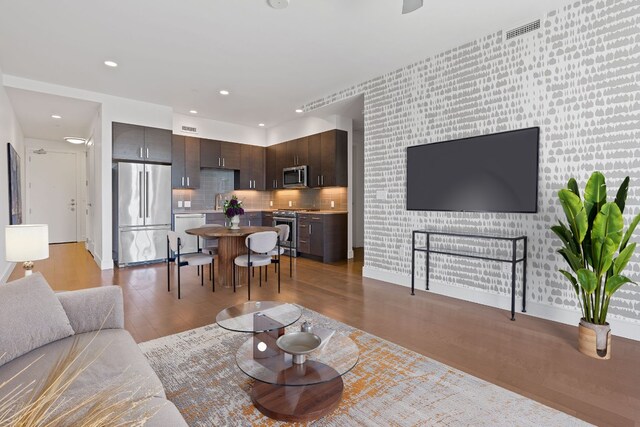 living room with visible vents, an accent wall, wood finished floors, and recessed lighting