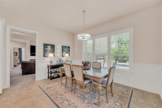 dining room featuring a decorative wall, a wainscoted wall, and light tile patterned floors