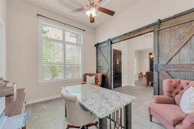 dining room with a barn door, a ceiling fan, and baseboards