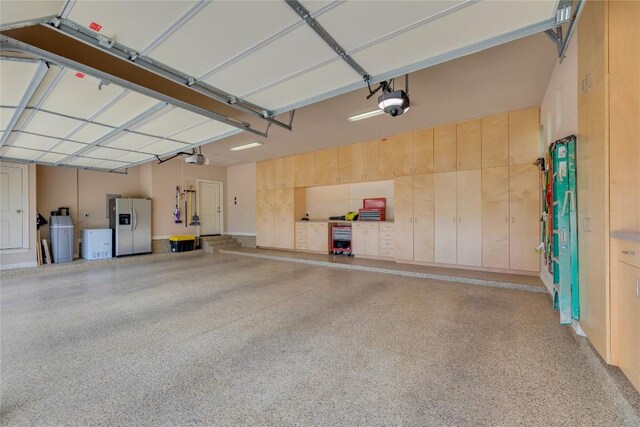 garage featuring stainless steel fridge and a garage door opener