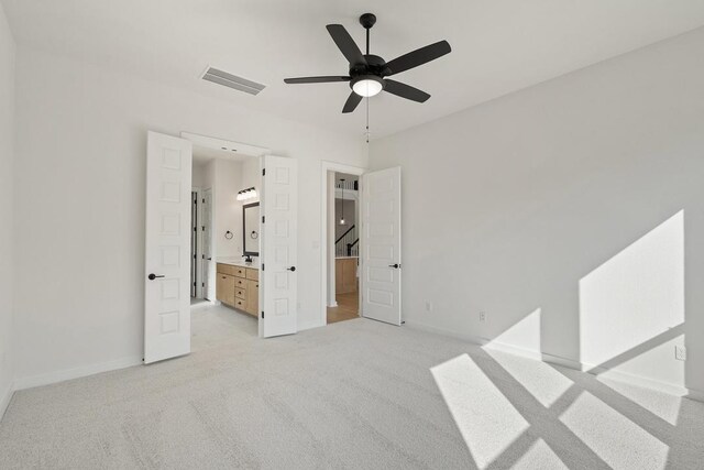 unfurnished bedroom featuring ceiling fan, light carpet, baseboards, ensuite bath, and visible vents