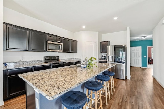 12700 Robert Taft St, Manor, TX 78653 - kitchen with appliances with stainless steel finishes, a breakfast bar, a kitchen island with sink, wood finished floors, and recessed lighting